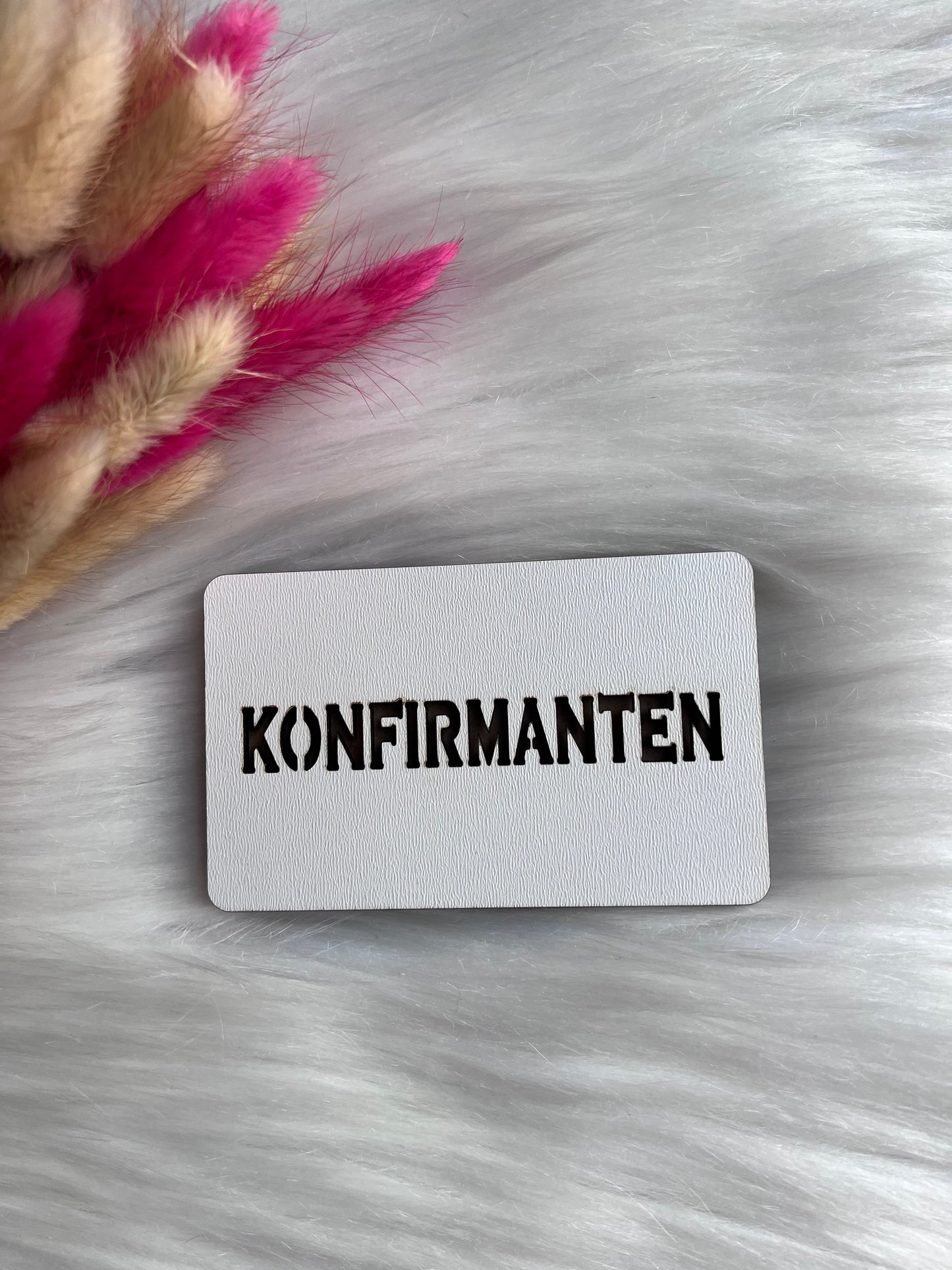 Håndlaget tre-etui KONFIRMANTEN med hvit badge på fluffy overflate
