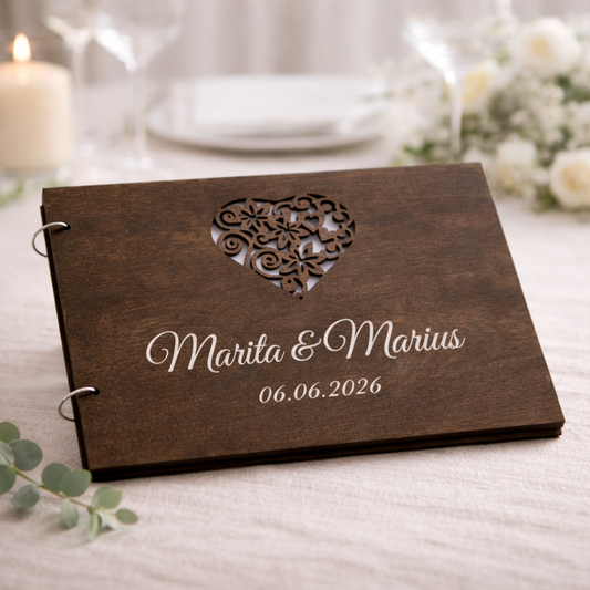 Personlig gjestebok i mørkt tre med gravert navn Marita & Marius og dato 06.06.2026, med dekorativt utskåret hjerte.