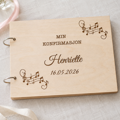 Lys konfirmasjonsbok i tre med gravert musikkmotiv og personlig tekst på forsiden