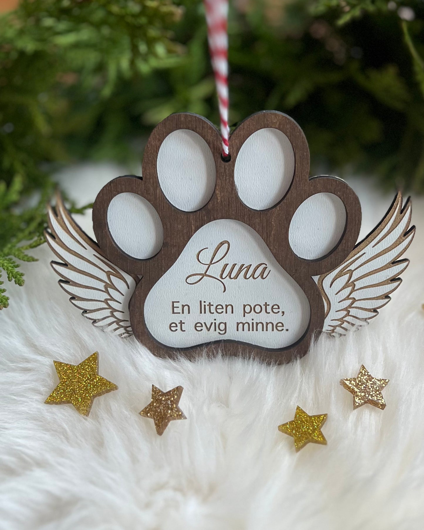 Håndlaget treornament for å minnes et kjæledyr, dekorert med englevinger.
