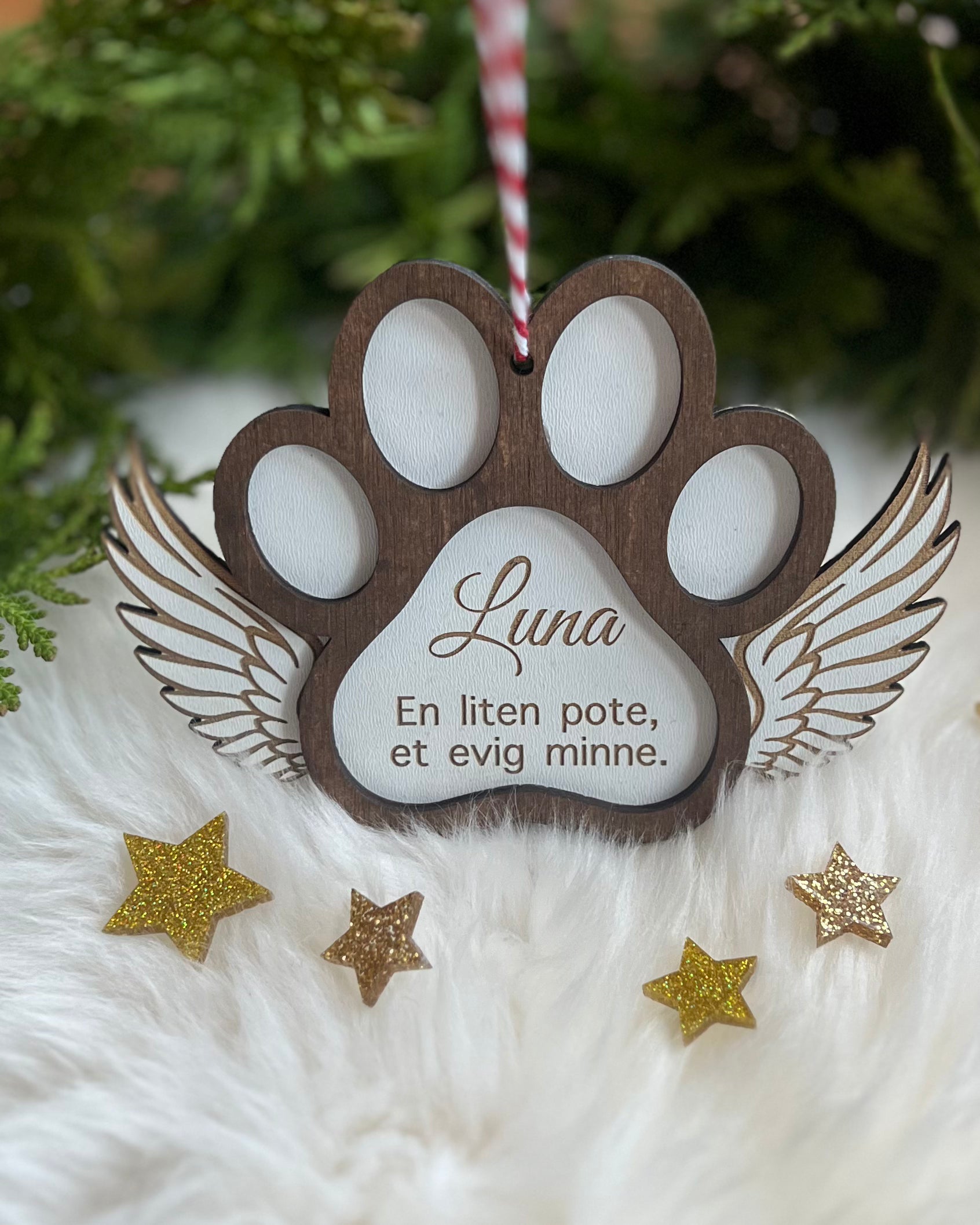 Håndlaget treornament for å minnes et kjæledyr, dekorert med englevinger.
