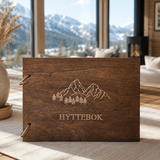 Brun hyttebok i tre med gravert skogmotiv, fjell og lukket omslag med metallringer