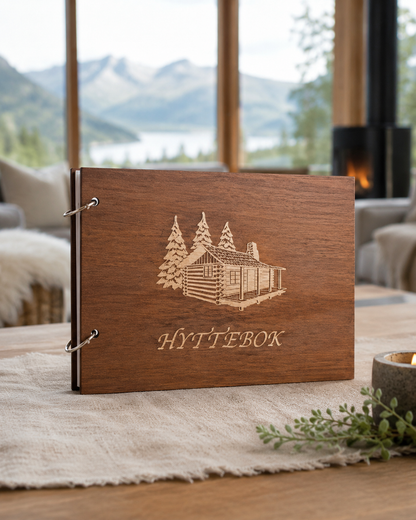 Brun hyttebok med gravert fjellmotiv på omslaget og mørk kontrast i motivet foran