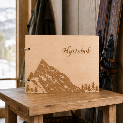 Hyttebok Slogen i tre med gravert fjellmotiv og tekst på lukket omslag med ringer