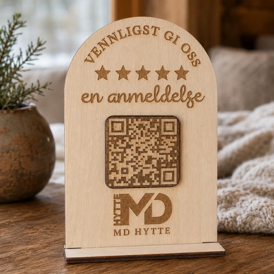 Skilt i tre med QR-kode og tekstfelt for anmeldelser, vist mot lys bakgrunn på bord