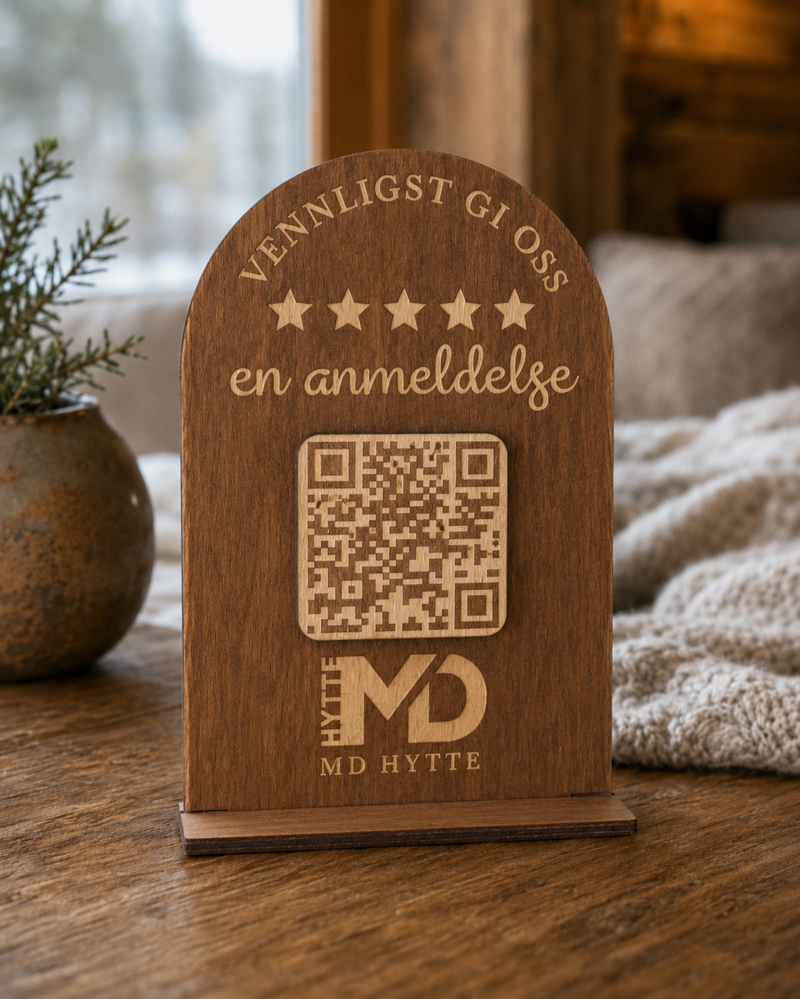 Brunt QR-skilt i tre på bord i et varmt hytteinteriør